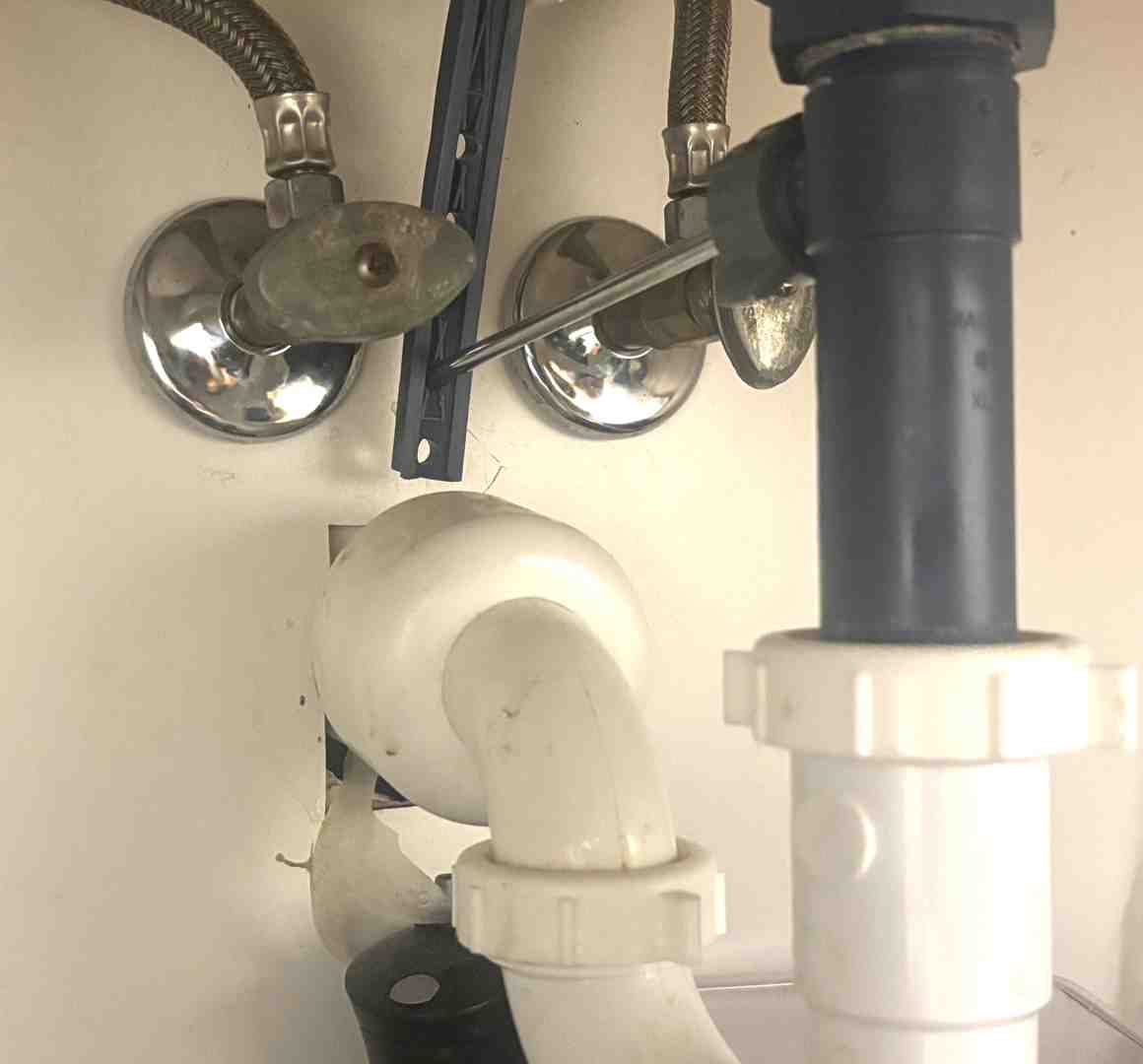 Hands of a plumber expertly repairing a leaky pipe under a kitchen sink. - St Charles plumbing company Hands of a plumber expertly repairing a leaky pipe under a kitchen sink. - St Charles plumbing company